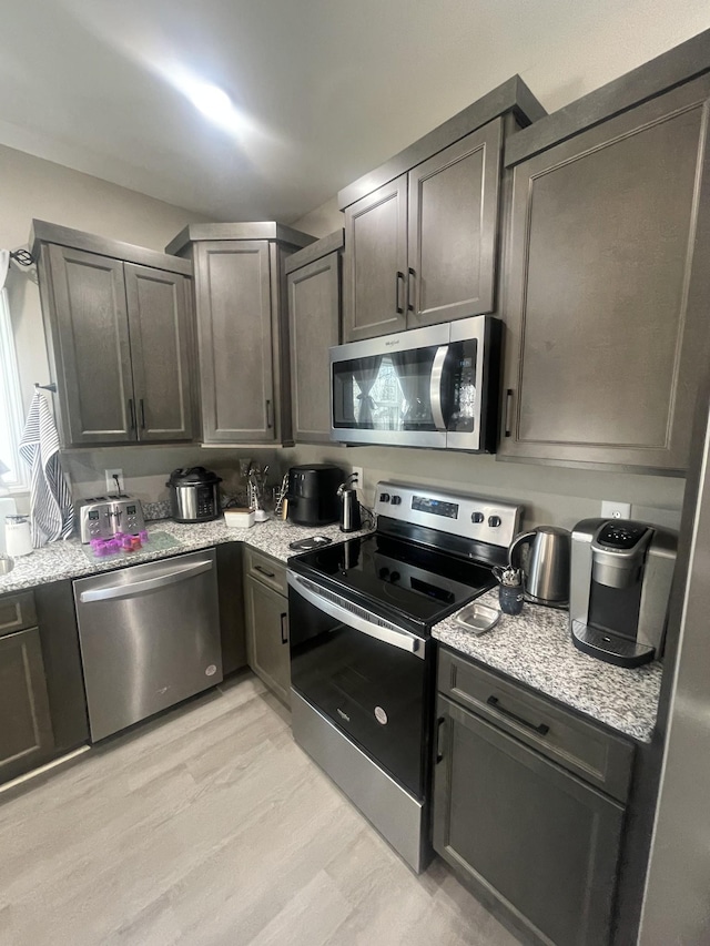 kitchen featuring light stone counters, light hardwood / wood-style flooring, and stainless steel appliances