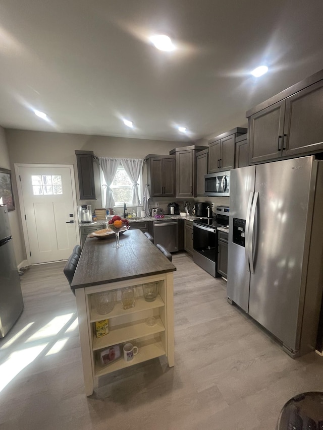 kitchen featuring dark brown cabinets, a center island, light wood-type flooring, and stainless steel appliances