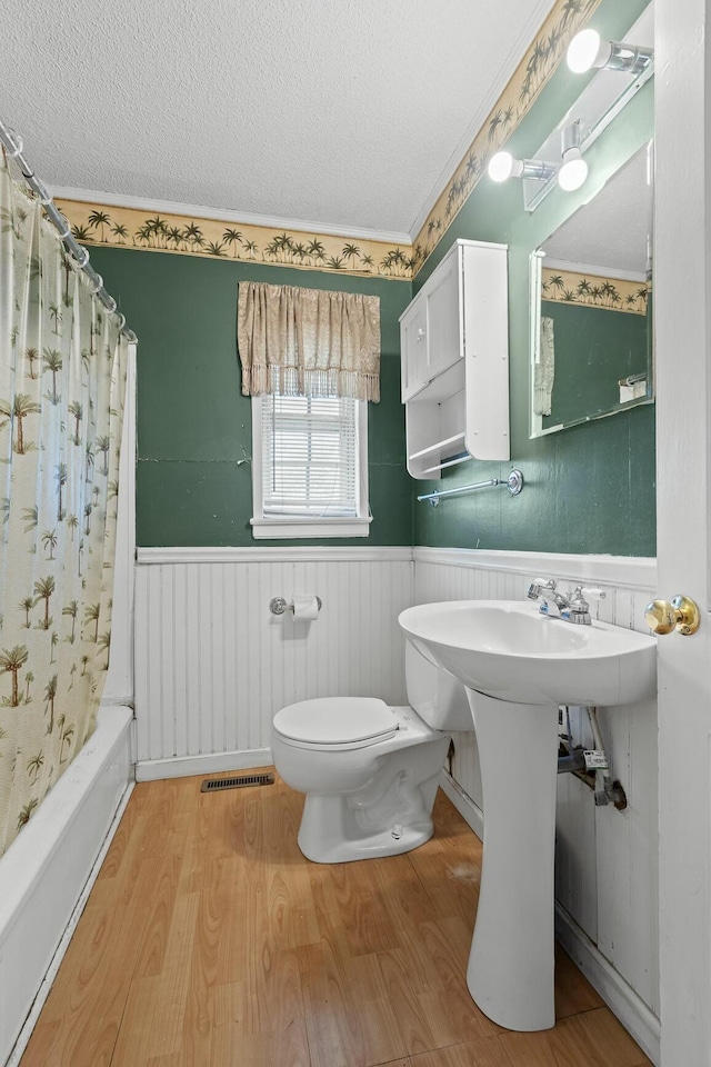 bathroom featuring toilet, shower / tub combo with curtain, a textured ceiling, and hardwood / wood-style flooring