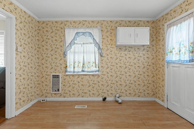 clothes washing area with heating unit, ornamental molding, and light wood-type flooring