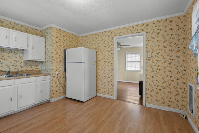 kitchen with white cabinetry, sink, light wood-type flooring, and white refrigerator