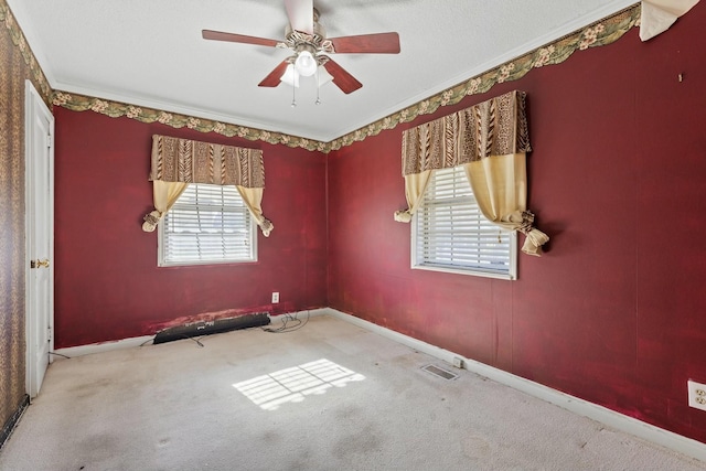 carpeted empty room with a textured ceiling, a wealth of natural light, ornamental molding, and ceiling fan