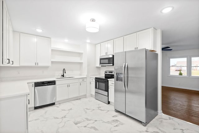 kitchen with stainless steel appliances, ceiling fan, sink, white cabinets, and light hardwood / wood-style floors