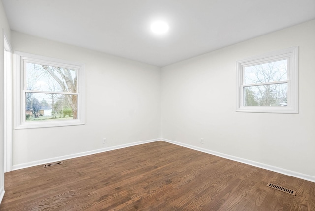 empty room featuring plenty of natural light and dark wood-type flooring