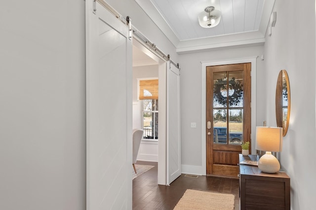 entryway with a barn door, a wealth of natural light, crown molding, and dark hardwood / wood-style floors