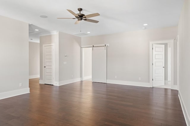 unfurnished room featuring a barn door, ceiling fan, and dark wood-type flooring