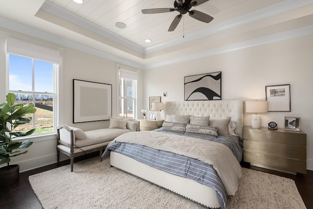 bedroom with ceiling fan, dark hardwood / wood-style floors, crown molding, and a tray ceiling