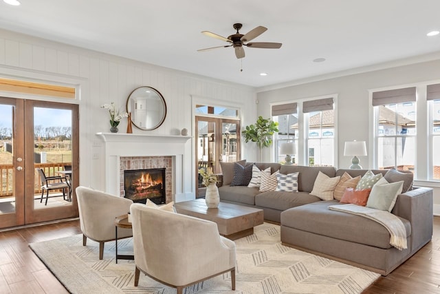 living room with french doors, light wood-type flooring, ceiling fan, and a healthy amount of sunlight