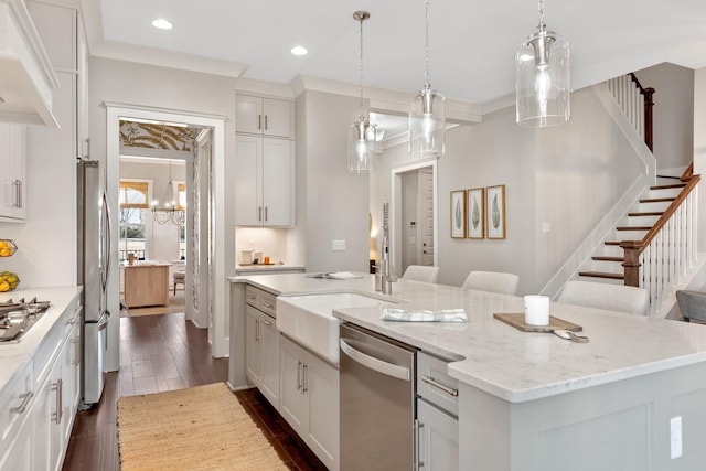 kitchen with a center island with sink, crown molding, dark hardwood / wood-style floors, appliances with stainless steel finishes, and white cabinetry