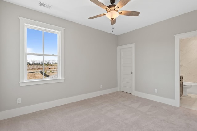 unfurnished bedroom featuring ensuite bath, ceiling fan, light colored carpet, and multiple windows