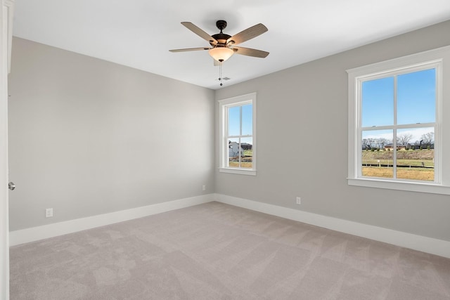 unfurnished room featuring ceiling fan, light colored carpet, and a wealth of natural light