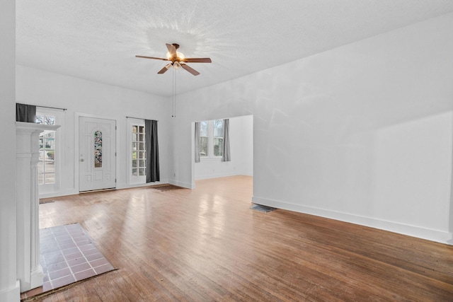 unfurnished living room with a textured ceiling, light hardwood / wood-style floors, a wealth of natural light, and ceiling fan