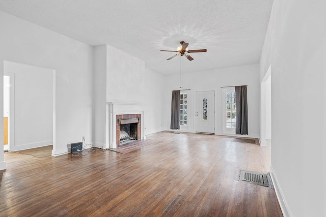 unfurnished living room featuring hardwood / wood-style floors, ceiling fan, a fireplace, and a textured ceiling