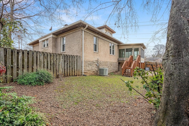 rear view of property with a lawn and central AC