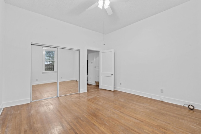 unfurnished bedroom featuring a high ceiling, a textured ceiling, light hardwood / wood-style flooring, and ceiling fan