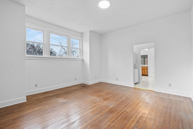 spare room with a textured ceiling and hardwood / wood-style flooring