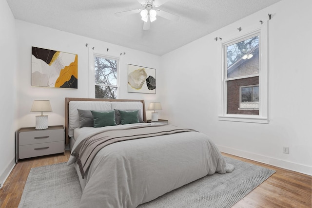 bedroom featuring ceiling fan, light hardwood / wood-style flooring, and a textured ceiling