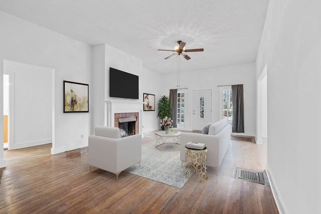 living room featuring ceiling fan, a fireplace, a textured ceiling, and hardwood / wood-style flooring