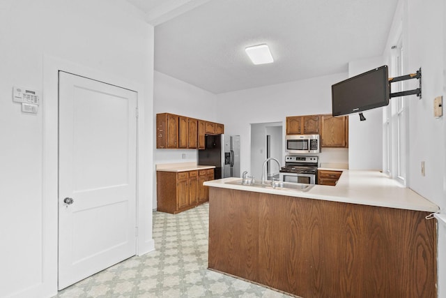 kitchen with kitchen peninsula, a textured ceiling, stainless steel appliances, and sink