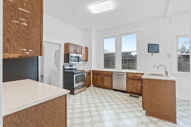 kitchen featuring a wealth of natural light, kitchen peninsula, sink, and appliances with stainless steel finishes