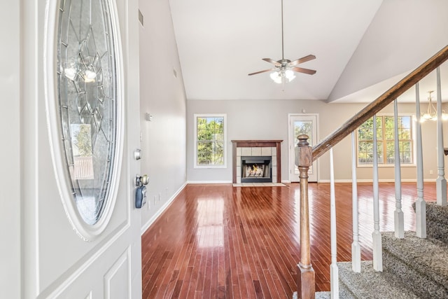 living room featuring a tile fireplace, hardwood / wood-style floors, ceiling fan with notable chandelier, and high vaulted ceiling