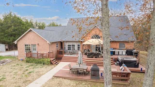 rear view of house with a hot tub and a deck