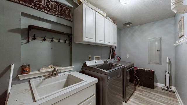 laundry room featuring cabinets, electric panel, sink, washing machine and dryer, and light hardwood / wood-style floors