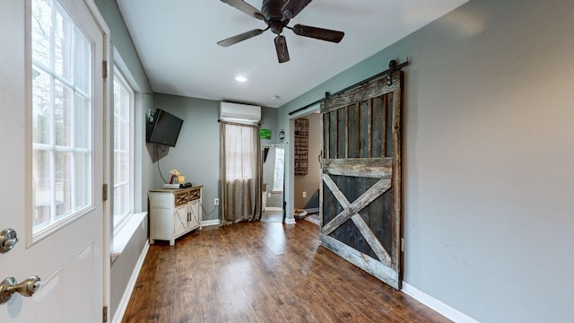 interior space with a barn door, a wall mounted AC, a healthy amount of sunlight, and ceiling fan