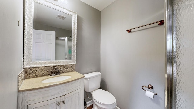 bathroom with decorative backsplash, vanity, a shower with shower door, and toilet