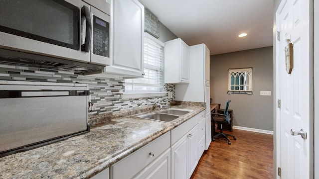 kitchen with backsplash, dark wood-type flooring, white cabinets, sink, and light stone countertops