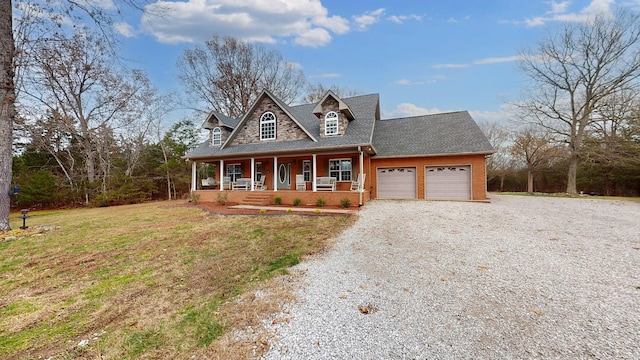 view of front of property featuring covered porch, a garage, and a front lawn