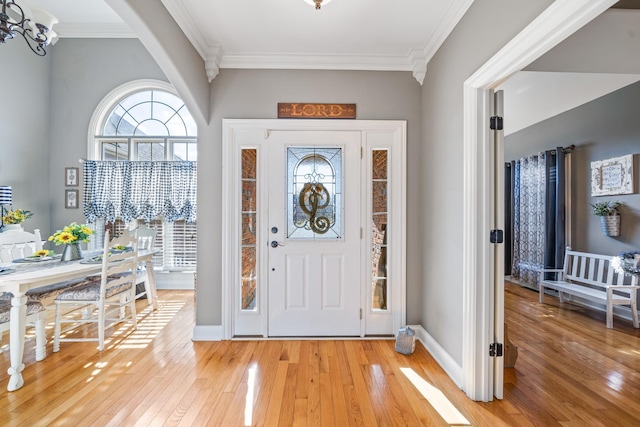 foyer with an inviting chandelier, light hardwood / wood-style flooring, and ornamental molding