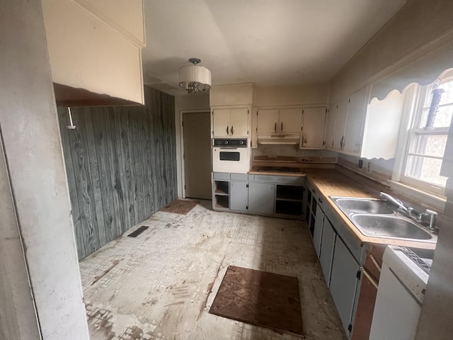 kitchen with white appliances, sink, and wooden walls