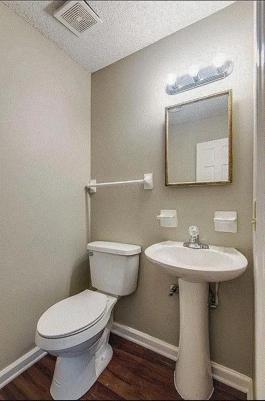 bathroom with hardwood / wood-style floors, toilet, and a textured ceiling