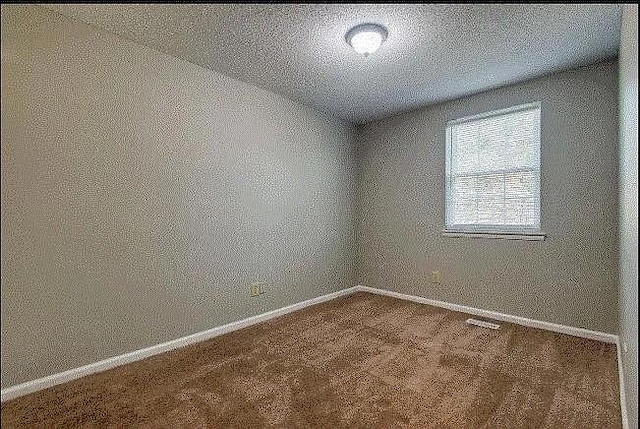 carpeted empty room with a textured ceiling