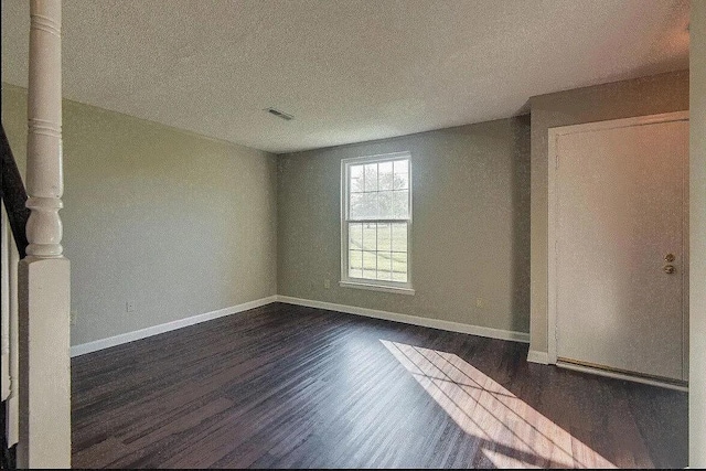 empty room featuring a textured ceiling and dark wood-type flooring