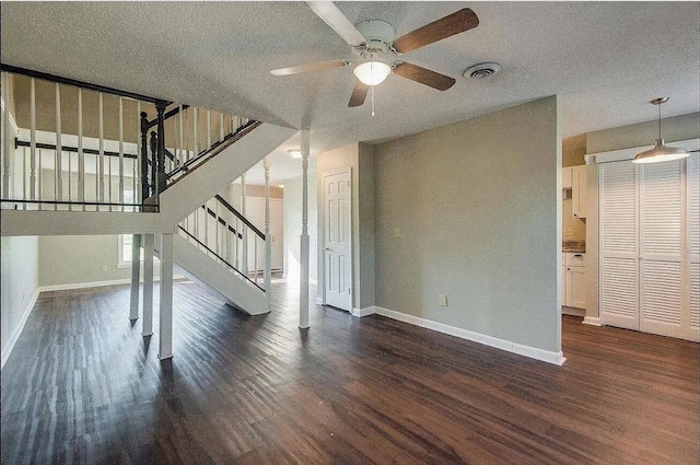 unfurnished living room with ceiling fan, dark hardwood / wood-style flooring, and a textured ceiling