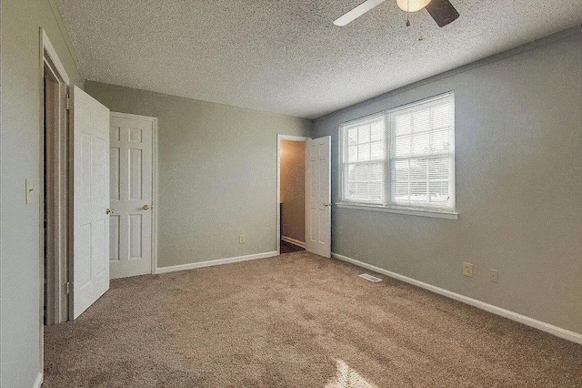 unfurnished bedroom featuring carpet, ceiling fan, and a textured ceiling