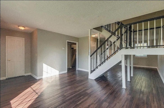 unfurnished living room featuring a textured ceiling and dark hardwood / wood-style flooring