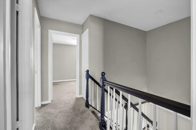 hallway with baseboards, an upstairs landing, and carpet flooring