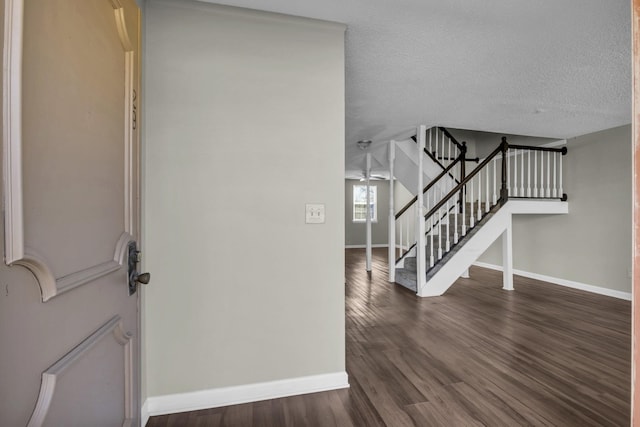 entryway featuring stairway, baseboards, a textured ceiling, and dark wood finished floors