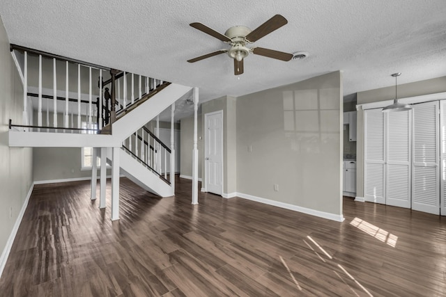 unfurnished living room featuring wood finished floors, visible vents, baseboards, stairs, and a textured ceiling