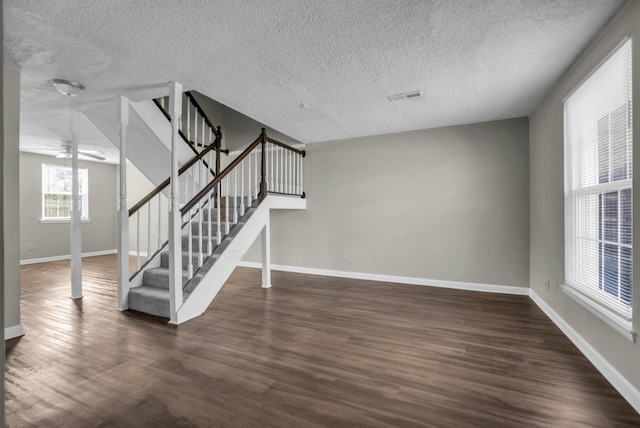 interior space with stairway, wood finished floors, visible vents, baseboards, and ceiling fan