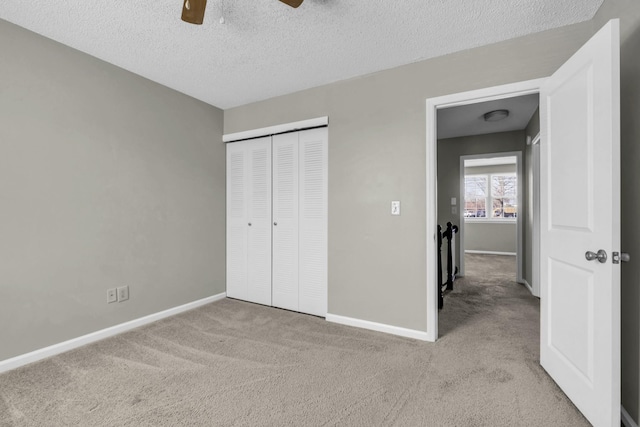 unfurnished bedroom with a closet, a textured ceiling, baseboards, and carpet