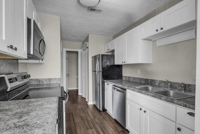 kitchen with visible vents, a sink, dark wood-style floors, appliances with stainless steel finishes, and white cabinets