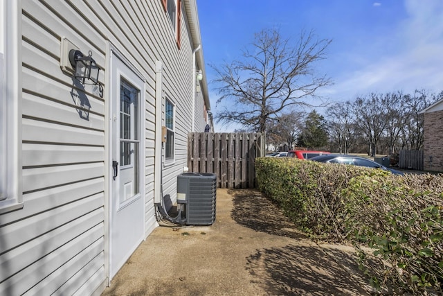 view of property exterior with central air condition unit and fence