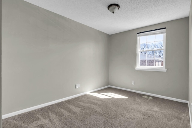 carpeted spare room featuring visible vents, baseboards, and a textured ceiling