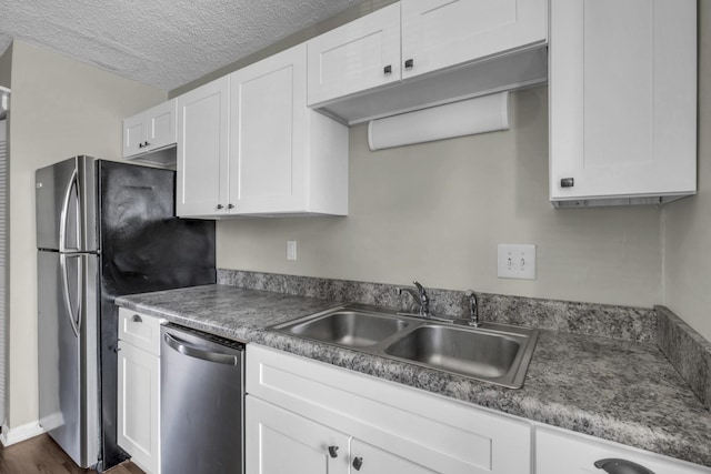 kitchen with a textured ceiling, white cabinets, appliances with stainless steel finishes, and a sink