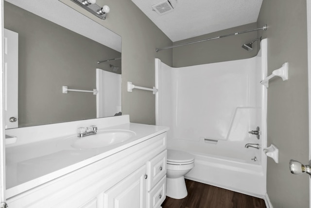 bathroom featuring vanity, wood finished floors, washtub / shower combination, visible vents, and toilet