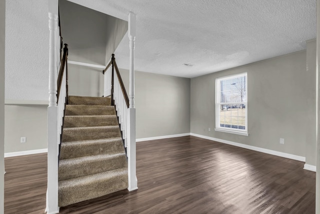 stairs featuring wood finished floors, baseboards, and a textured ceiling